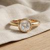 9ct gold bezel solitaire with moissanite resting on linen - Minted Jewellery