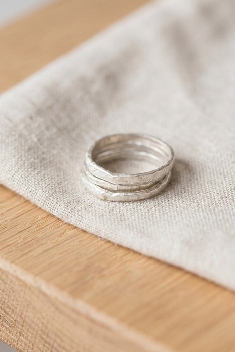 Silver organic stacking ring set resting on linen - Minted Jewellery