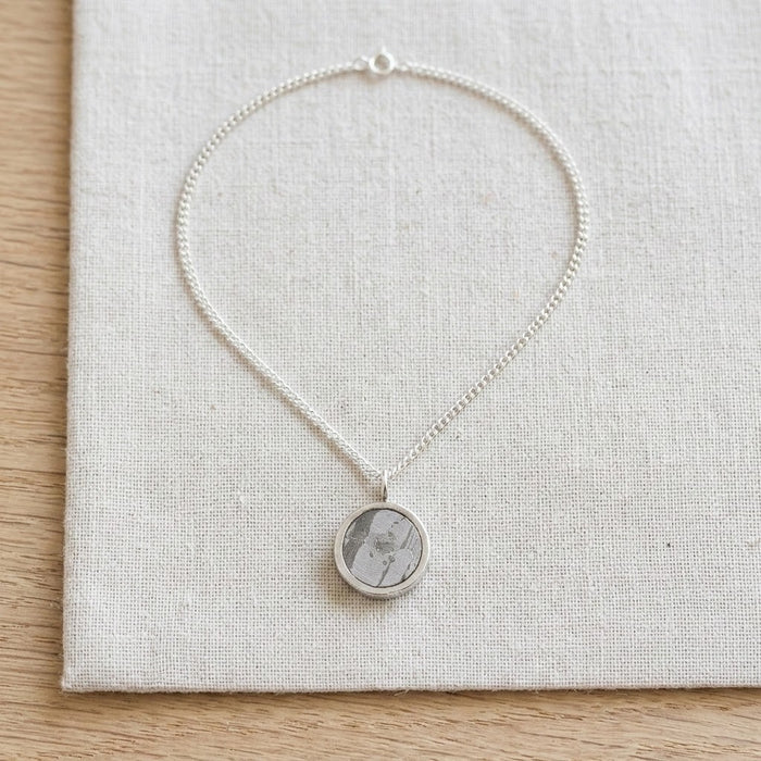 Round meteorite necklace resting on linen - Minted Jewellery