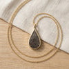 Seymchan meteorite teardrop necklace in yellow gold, on linen - Minted Jewellery