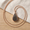 Seymchan meteorite teardrop necklace in rose gold, on linen - Minted Jewellery