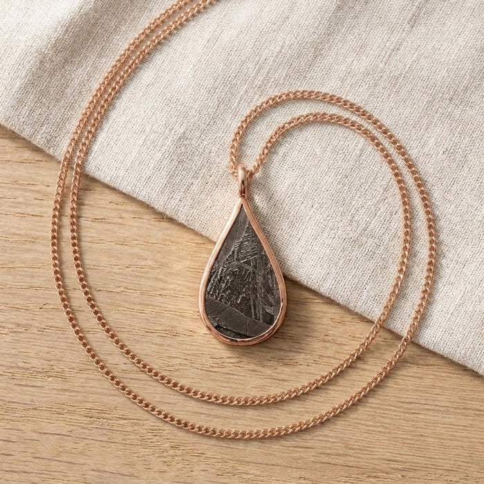 Seymchan meteorite teardrop necklace in rose gold, on linen - Minted Jewellery