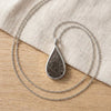 Seymchan meteorite teardrop necklace in silver, on linen - Minted Jewellery