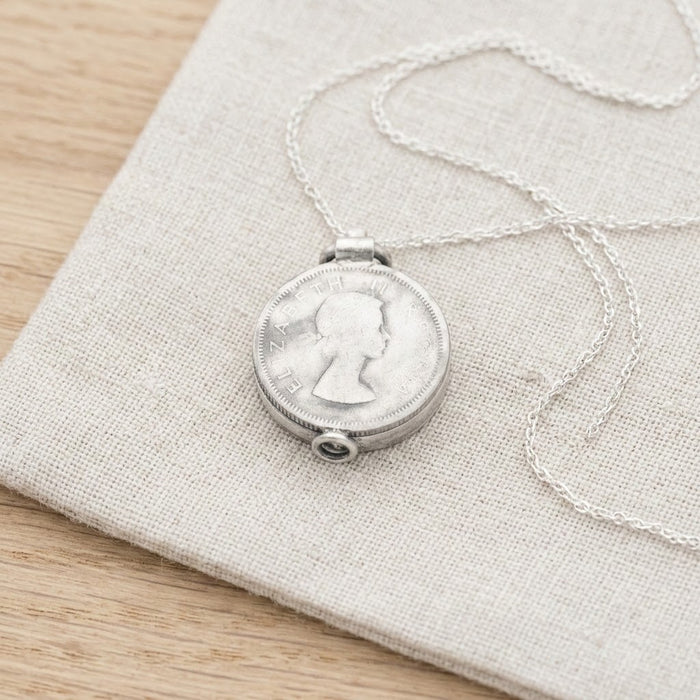 Silver coin locket necklace resting on linen - Minted Jewellery